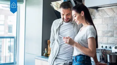 A couple with a smartphone standing in the kitchen