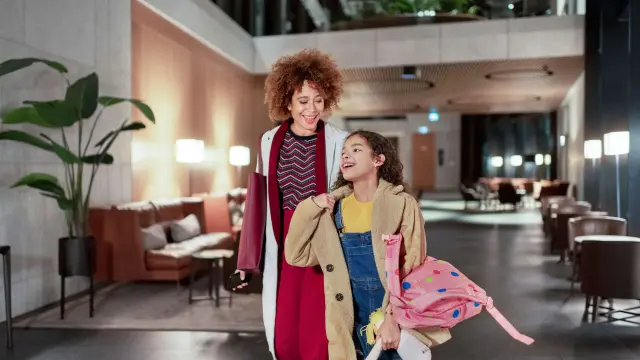 An adult and a child walk together through a modern, warmly lit lobby.