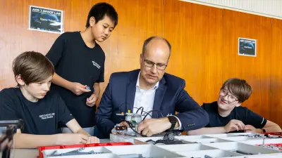 Students assemble and program a small robotics model with electronic components on a table