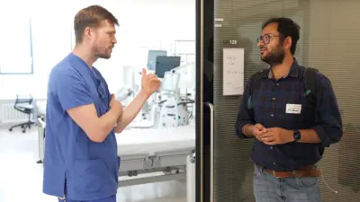 A medical professional of the Bosch Health Campus and a hackathon participant form Bosch Research discuss in a clinic setting at the Bosch Health Campus.
