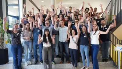 Attendees of the Bosch AI Hackathon celebrating on a staircase, waving their hands after the event.