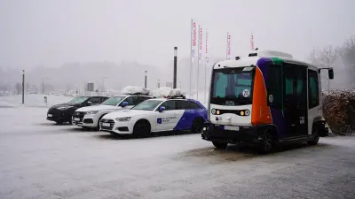 Four demonstrator vehicles from the "KIsSME" funding project in front of the main entrance to the main building of Bosch Research.