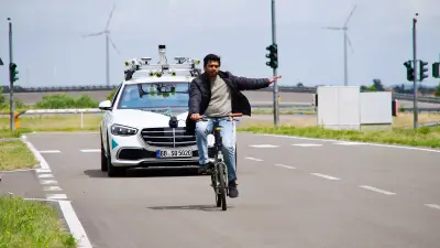 A testing vehicle by STADT:up driving behind a cyclist.