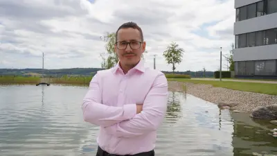 Damir Shakirov stands with his arms crossed in front of a pond.