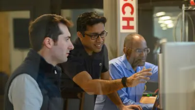 Samarjit Das und zwei weitere Personen diskutieren ein Projekt, das auf einem Computerbildschirm angezeigt wird.