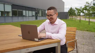 Damir Shakirov working outdoors on laptop.