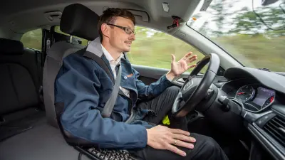 Driver in a car, not touching the steering wheel.