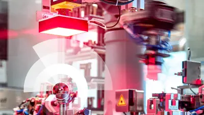 Die vom BCAI entwickelte AI Analytics Platform analysiert Fertigungsprozesse und hilft diese zu optimieren. Auf dem Bild sind Fertigungsmaschinen zu sehen, die in Hintergrund leicht verschwommen dargestellt werden. Im Vordergrund ist eine Halbkreisgrafik zu erkennen, die die Optimierung der Fertigungsprozesse visualisiert.