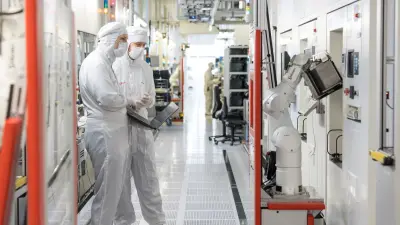 Zwei Forscher stehen in weißer Schutzkleidung in einem Reinraum bei Bosch Research und halten einen Laptop in der Hand. Nur ihre Augen sind sichtbar. Ihr Blick ist prüfend auf einen Roboter gerichtet, der sich rechts im Bild befindet. Das Bild illustriert den vielfältigen Einsatz von Künstlicher Intelligenz (KI) in der Fertigung, insbesondere zur Erkennung von Anomalien.