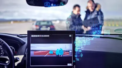 View of the road from an automated vehicle. Pedestrians, vehicles, and the roadway are marked on the screen in the vehicle.