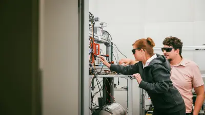 Bosch research experts Janine Riedrich-Möller and Riccardo Cipolletti in the Quantum Lab in Renningen, Germany. Both wear protective goggles while handling a device.