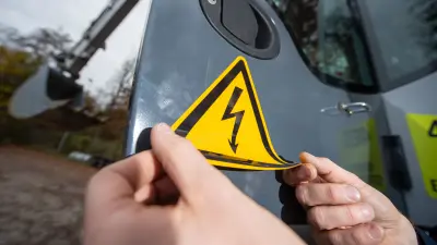 Image of an electric excavator with a warning label. Bosch Research is researching, among other things, how to significantly reduce construction machinery emissions in urban areas.