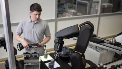 A Bosch employee is working together with the APAS assistant. The sensor skin developed by Bosch enables a contact-free cooperation of man and machine.