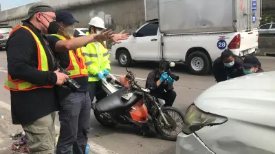 Bosch-Forschungsexperte Thomas Lich bei der Unfallaufnahme in Thailand. Thomas hat eine Kamera in der Hand und untersucht eine Unfallstelle.