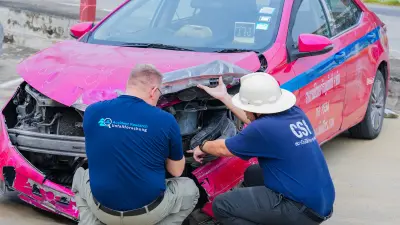 Bosch accident researcher Thomas Lich examines a pink taxi after an accident in Nonthaburi, Thailand.