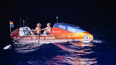 Two person rowing in a boat at night.