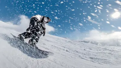 Snowboarder Yanneck Konda riding down a mountain as stirred-up snow rushes against him.