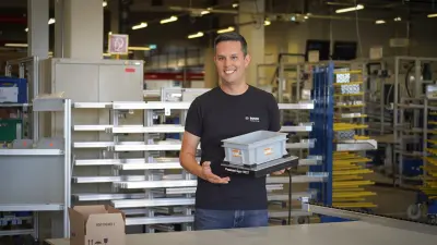 Bosch Researcher Marian holding a part of his machine CESA³R at the production hall of Bosch Rexroth, Stuttgart, Germany.
