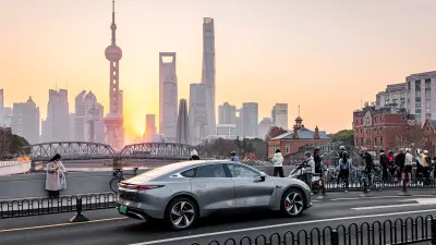 Car on a bridge with pedestrians and city skyline in the background