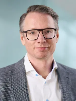 Person wearing a jacket and shirt against a neutral background