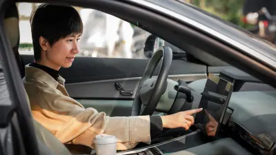 Person operating a car touchscreen from the driver’s seat