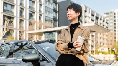 Person standing next to a parked car holding a takeaway cup