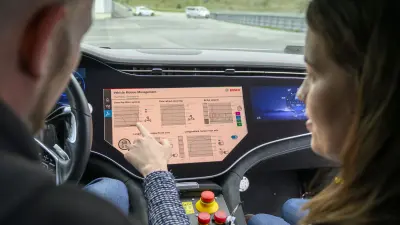 Two people evaluating data on a dashboard inside a car.