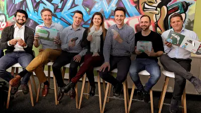 Seven members of the Ixo team in front of a graffiti-sprayed wall in their office