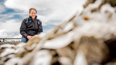 The Bosch agronomist Jesse Reader on the beach, next to a mountain of oysters
