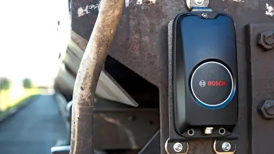 A box with sensors, known as the AMRA system, attached to the exterior of a freight car.