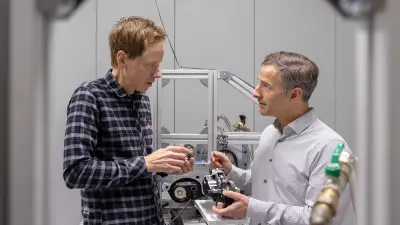 Two people inspecting an e bike motor on a testing frame in a workshop.