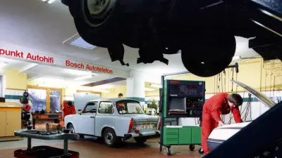 A Bosch service center with mechanics working on a Trabant and another vehicle.