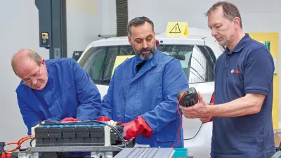 Technicians inspecting an electric car battery.