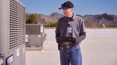A technician is inspecting an air conditioning unit on the roof of a school.