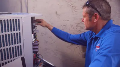 Technician Gabe Bond is checking the climate technology behind a house. The interior of the machine is visible