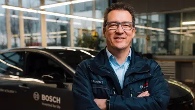 Hagen Kuckert lächelt und steht vor einem Auto.