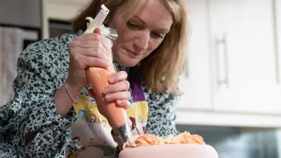 Eine blonde Frau, Mary Houlihan, verziert eine Torte mit einer Spritztülle.