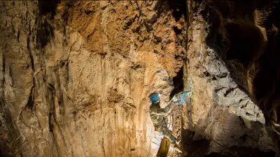 Ein Höhlenforscher klettert eine Felswand hinauf.
