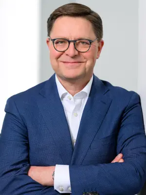 Das Bild zeigt Stefan Grosch, Geschäftsführer und Arbeitsdirektor der Robert Bosch GmbH. Er trägt einen Anzug, hat die Arme verschränkt und lächelt in die Kamera.