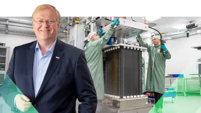 Stefan Hartung stands in the foreground, while in the background, workers assemble a fuel cell stack in a factory setting.