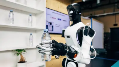 Ein humanoider Roboter mit Bosch-Sensoren hält eine Wasserflasche in seiner feinfühligen Roboterhand.