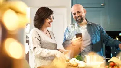 Ein Ehepaar reguliert zu Hause die Heizung mit einer Smart Home App.
