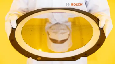 Ein Forscher hält einen Bosch-Wafer im Reinraum der Wafer-Fab in Dresden in den Händen.