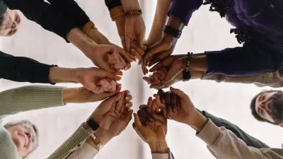 Different people hold their hands together in a circle.