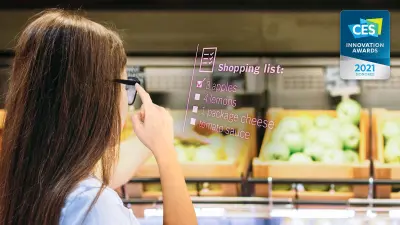Eine Frau steht in der Gemüseabteilung eines Supermarktes und bekommt über ihre intelligente Brille weitere Informationen eingeblendet