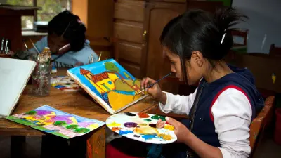 Zwei Kinder aus Munaychay, Peru, sitzen an einem Tisch und malen