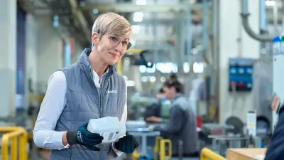 Woman with short blonde hair holds a large white plastic container in her hand.