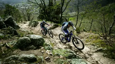 Two eMountainbikers ride over stony and hilly terrain and scale the mountain.