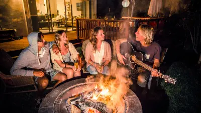 The image shows people sitting around a fire partying.
