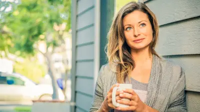 Helen Schettini is leaning against a wall and drinks coffee.